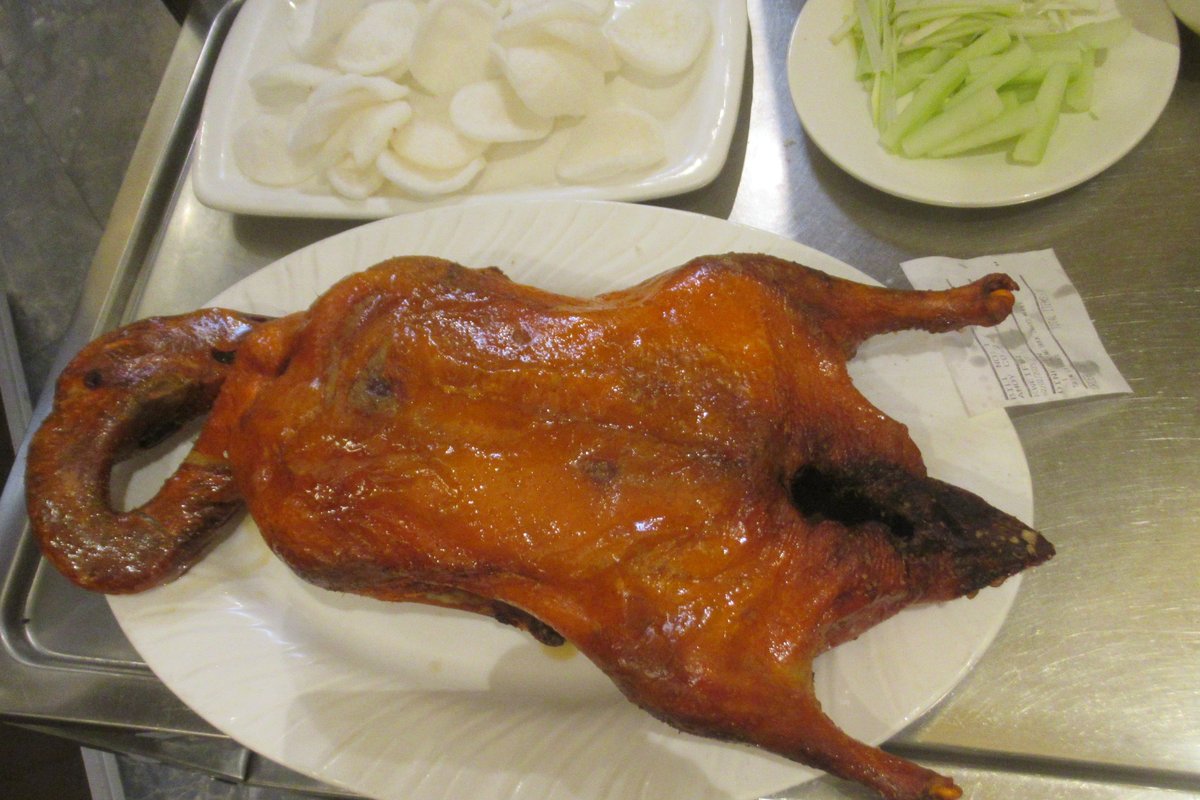 Cantonese roast duck with crispy golden skin, served with cucumber and bao buns