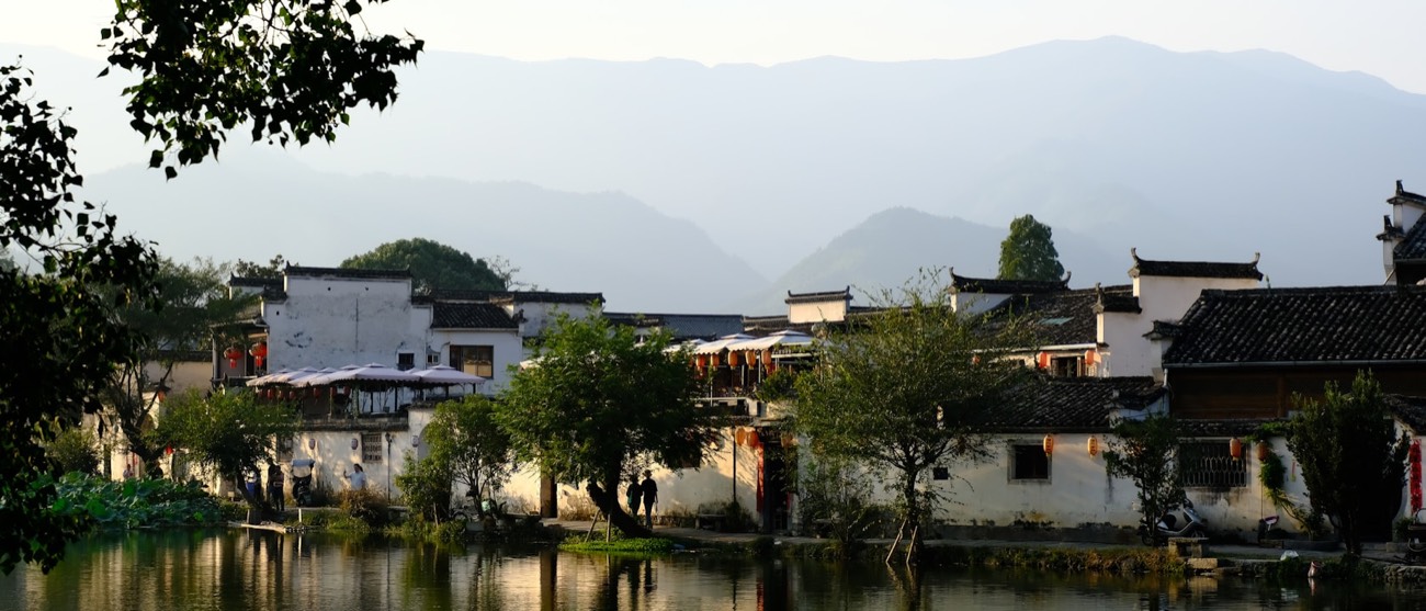 Fuzhou riverside historic quarter — traditional white-walled architecture reflected in water, with mountains beyond