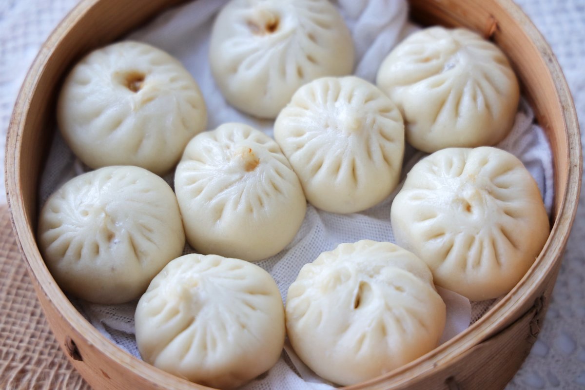 Shanghainese xiaolongbao soup dumplings in a bamboo steamer basket, delicately pleated