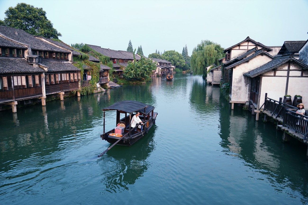 A boat glides between traditional houses in Wuzhen water town