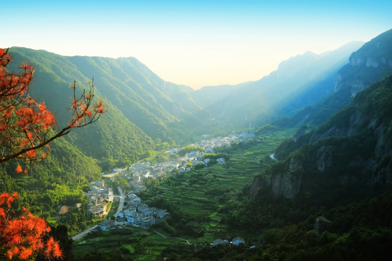 A misty mountain valley with a village among green terraced hills near Wenzhou, Zhejiang