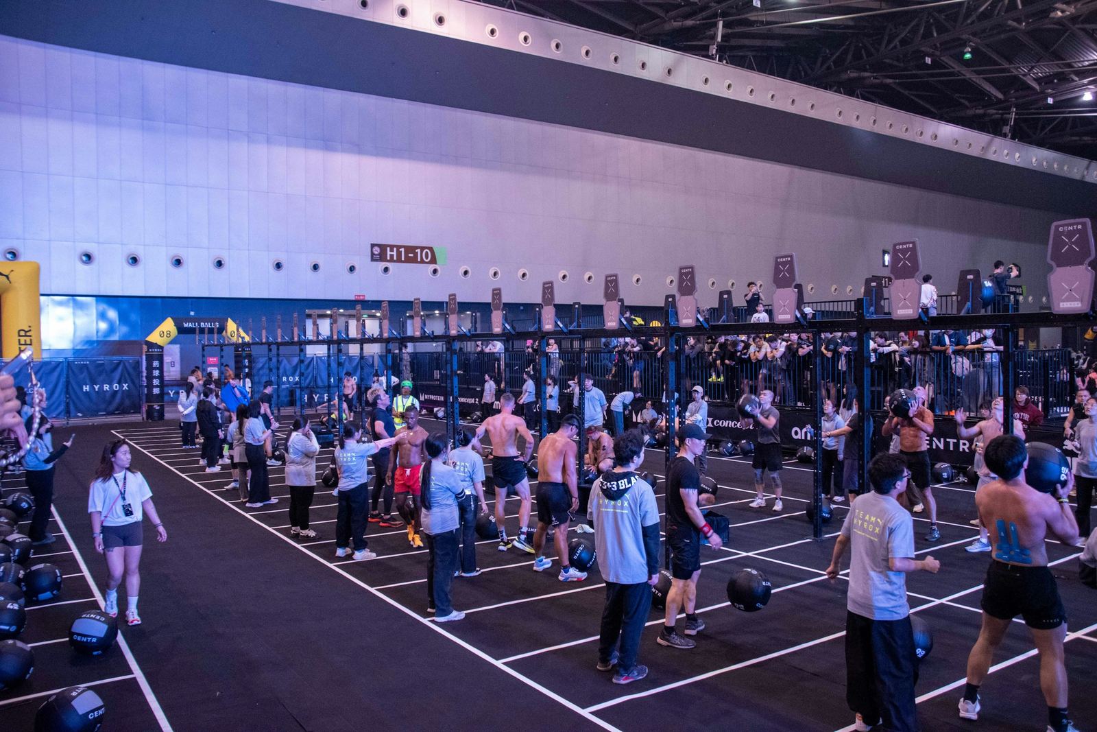 Hundreds of competitors spread across the marked lanes of an indoor Hyrox race floor