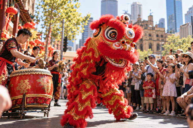 A lion dance in an Australian city street, red and gold costume mid-movement, a crowd watching.
