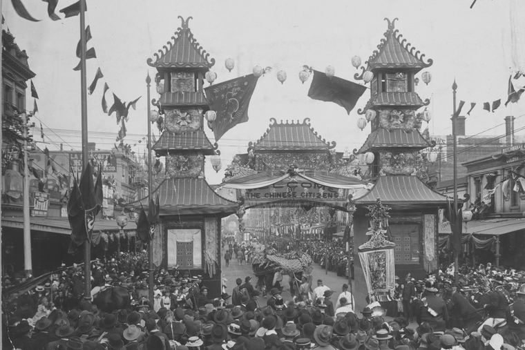 Melbourne's Chinese citizens' welcome arch in 1901, two pagoda towers above a crowd, a banner reading Welcome by the Chinese citizens: a landmark in the history of Chinese Australians.