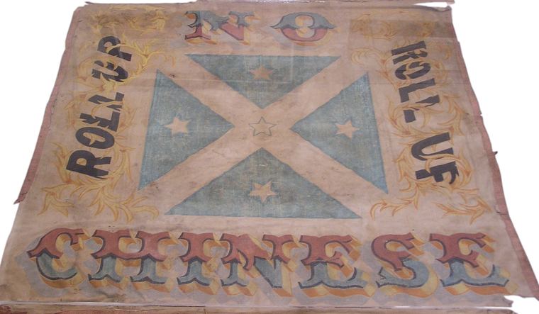 The painted Lambing Flat banner of 1861, a blue cross on a pale field with the words Roll up, Roll up, No Chinese.