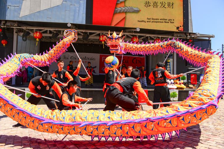 Dancers in black and red holding up a bright orange and purple dragon for Lunar New Year in Federation Square, Melbourne, in 2014.