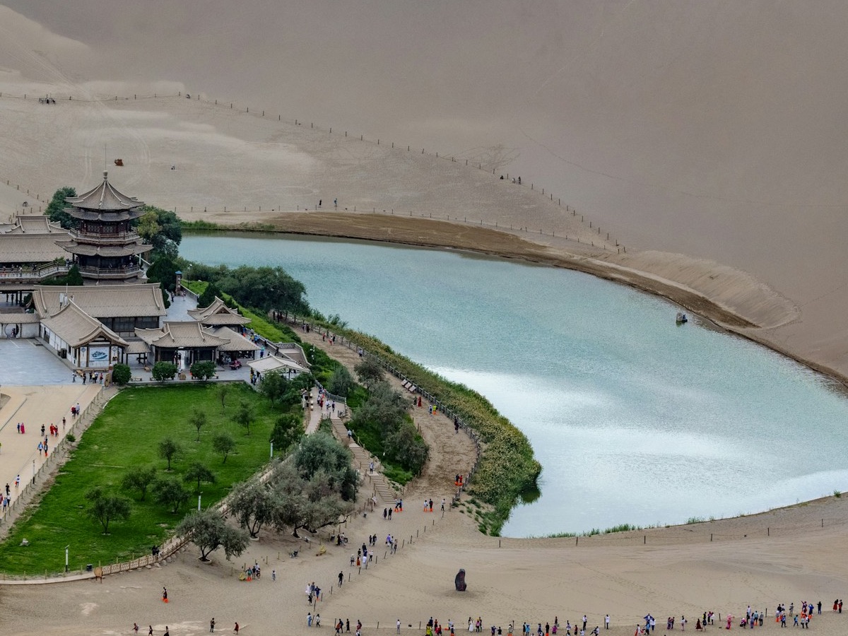 Aerial view of the Crescent Lake oasis with traditional pagodas surrounded by Mingsha sand dunes, Dunhuang, Gansu