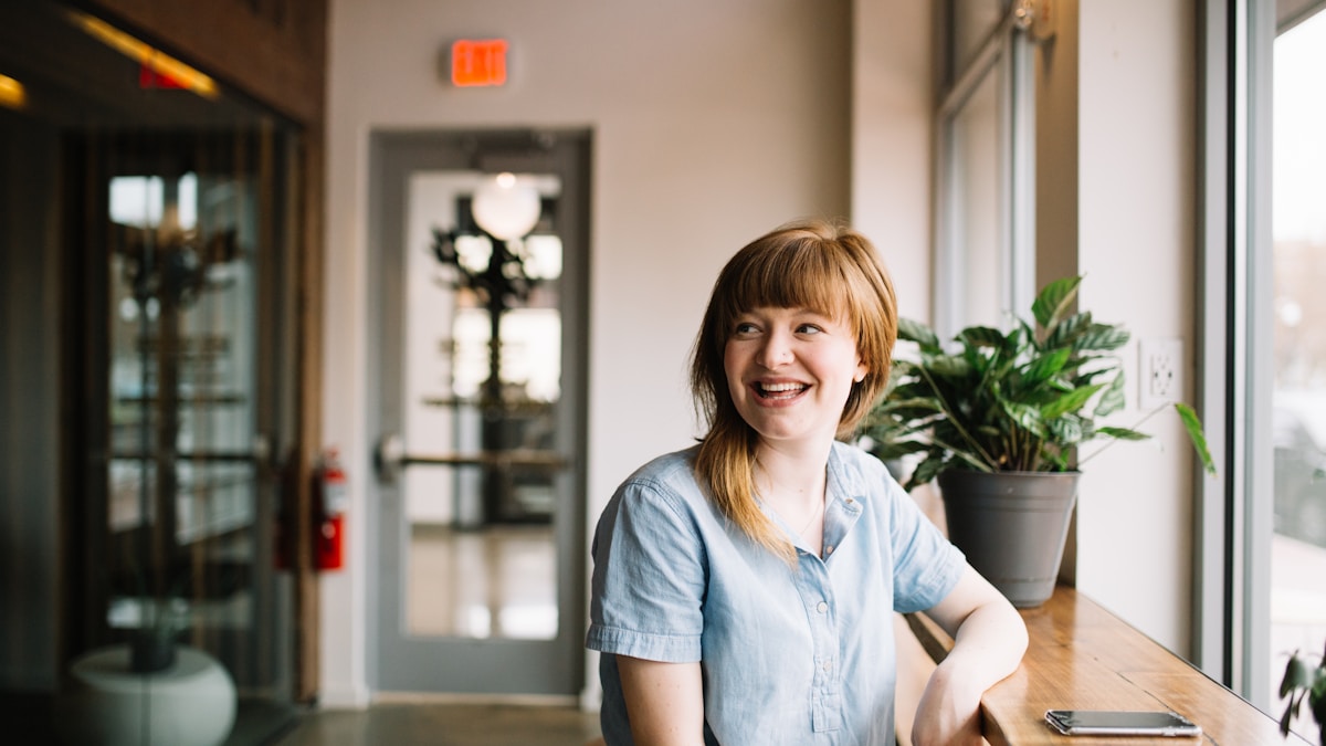 A young professional working at a wooden table by a window — the kind of self-directed career investment Mandarin lessons fit into