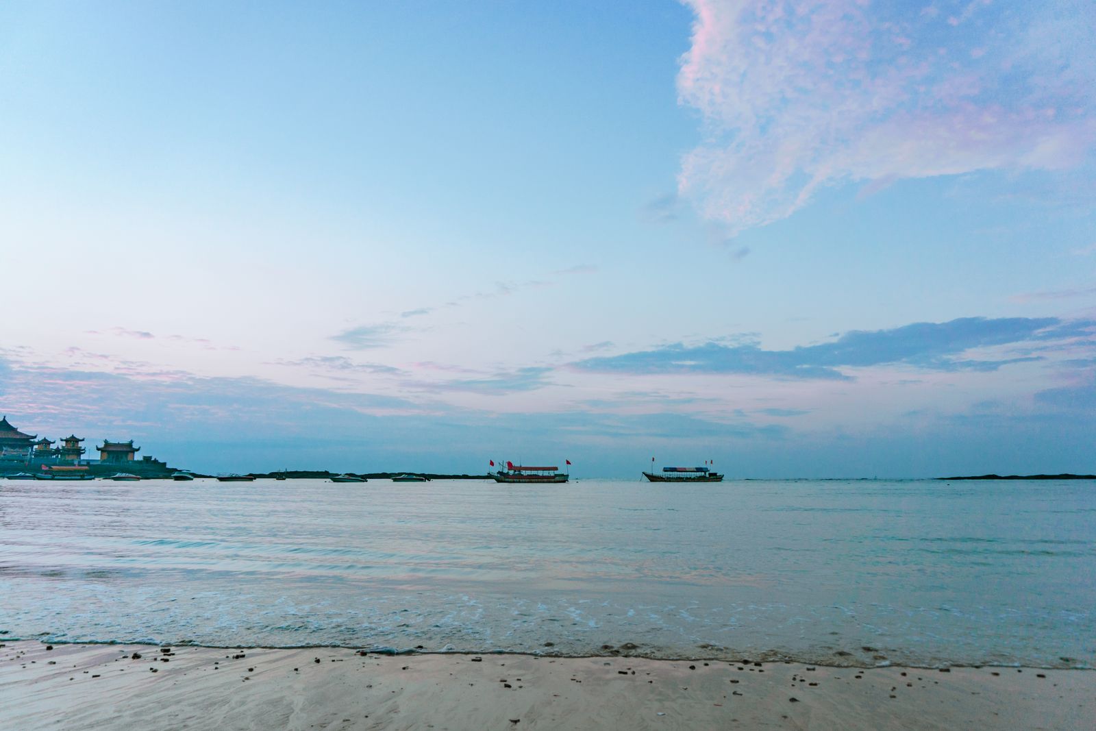 Fishing boats moored off a calm sandy beach at dusk, Beihai, Guangxi