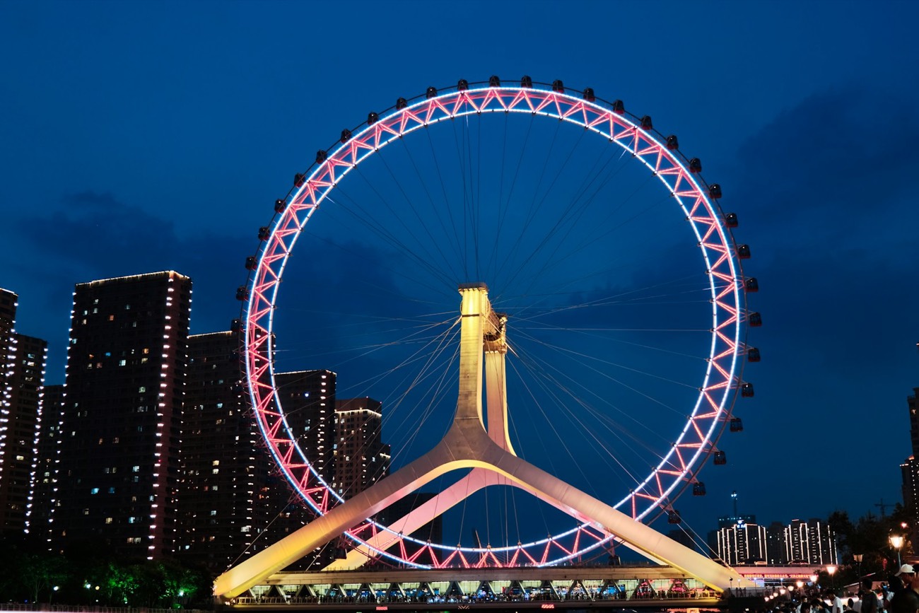 The Tianjin Eye ferris wheel lit up over the Yongle Bridge at dusk