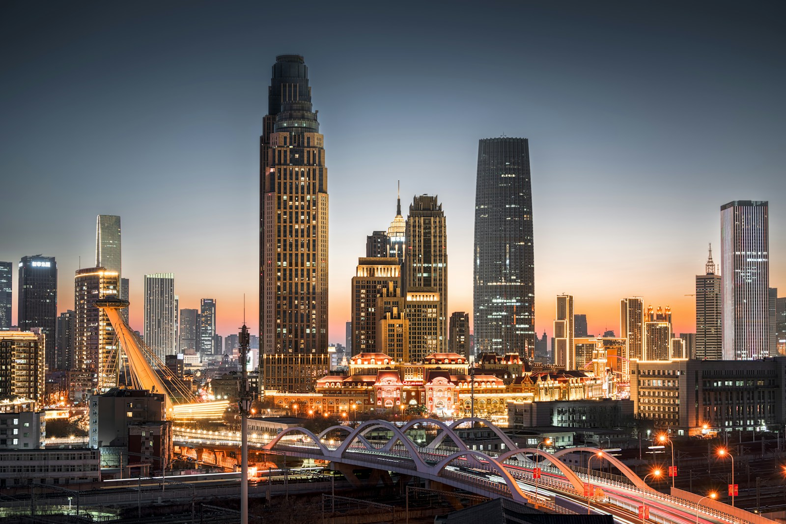 Tianjin’s skyline at dusk above the Hai River, the lit old town below the towers