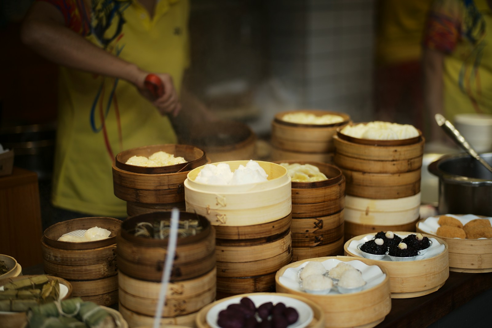 Stacked bamboo steamers of buns and dumplings at a busy Chinese street-food stall