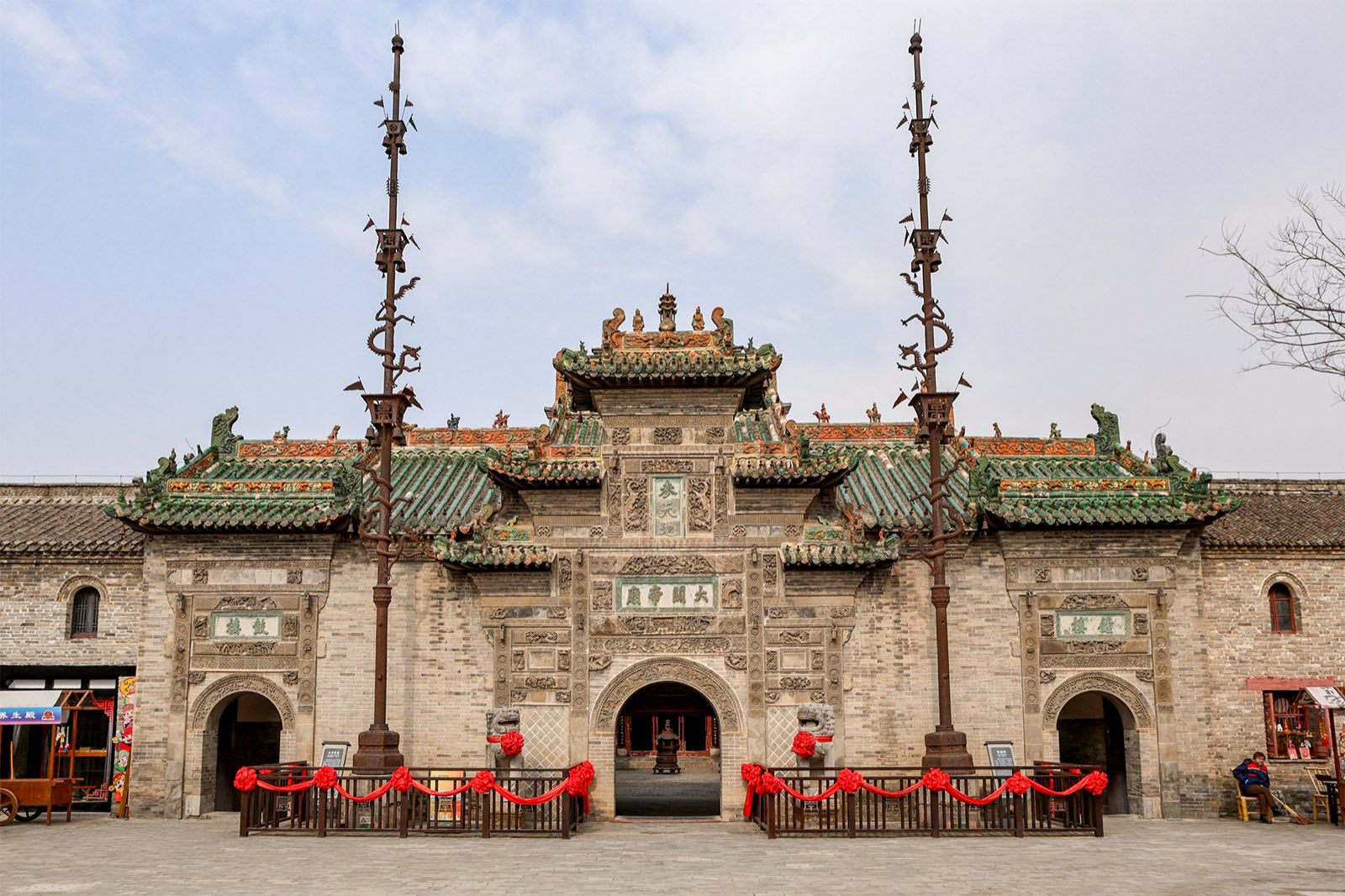 The carved brick gateway of the Huaxi Lou guild hall in Bozhou, with its twin iron flagpoles